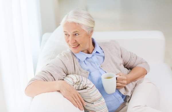 Anciana se relaja en el sofá con una taza de té